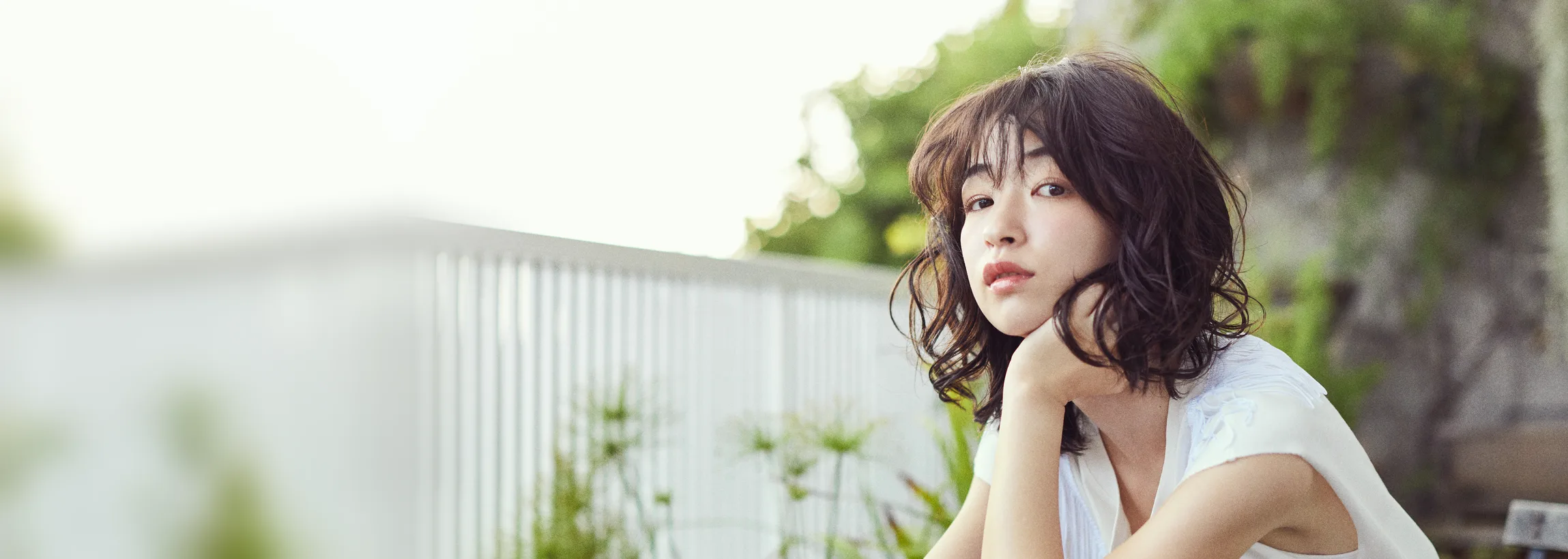 バンコク・トンローのヘアサロン BALCONY。テラスで頬杖をつく、ウェーブのボブの女性
